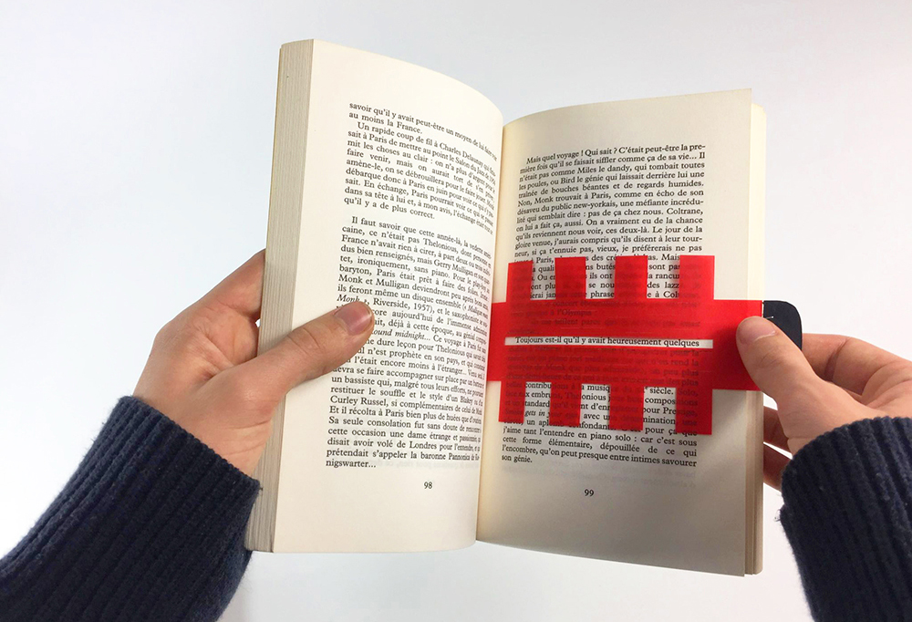 photographie en point de vue subjectif d'un livre ouvert avec un marque page rouge à l'intérieur.