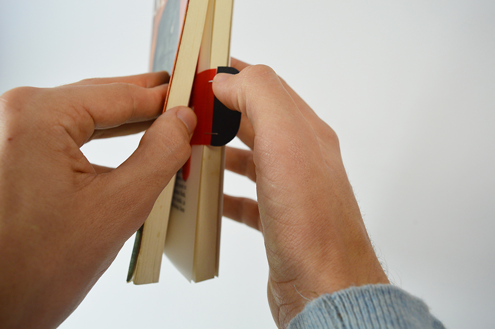 photographie de mains en gros plan qui ouvrent un livre à l'aide d'un marque-pages.