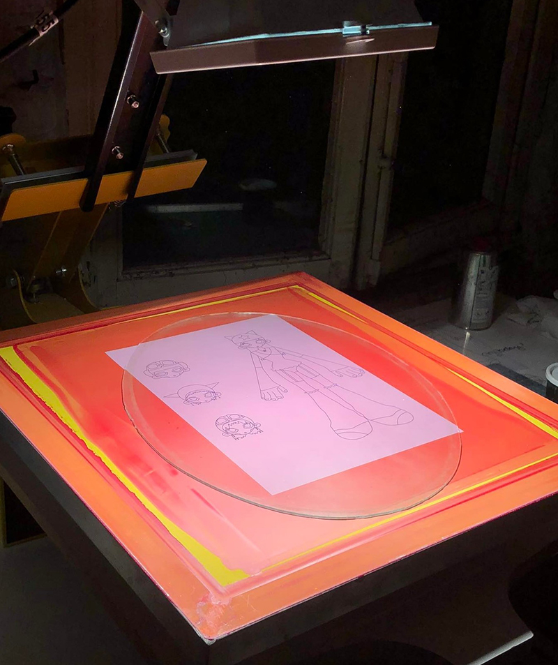 photographie d'une table de sérigraphie rouge avec un dessin linéaire sur calque placé dessus.