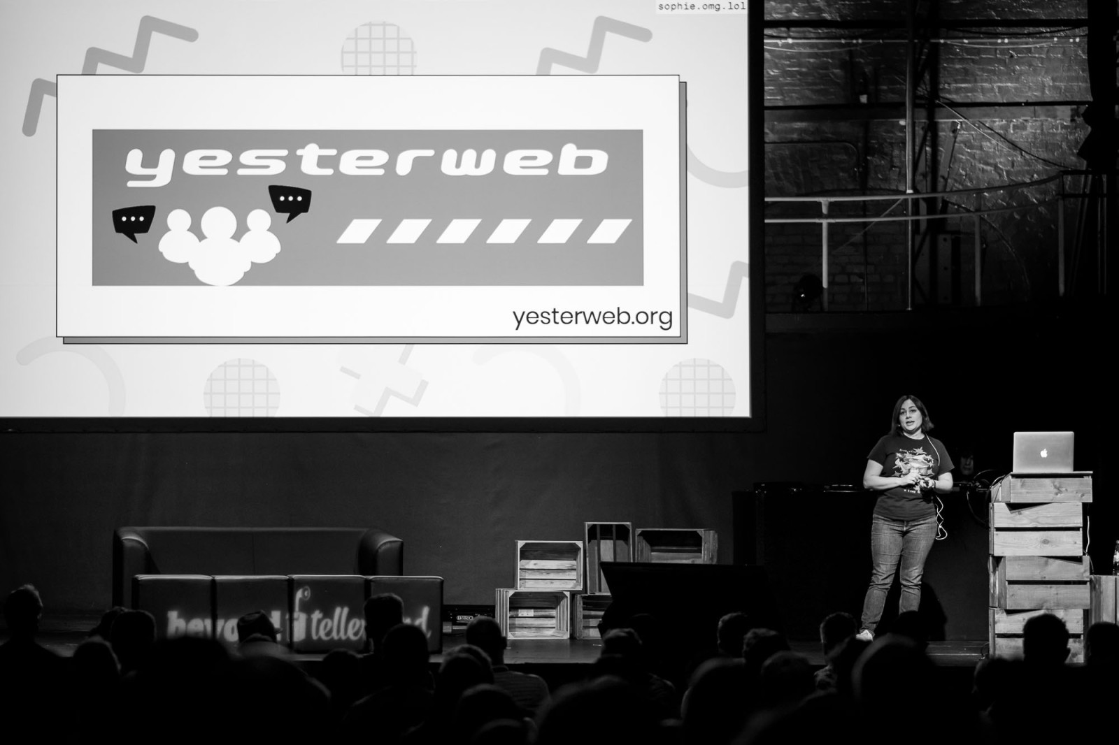 Sophie Konnin de plein-pied en train de présenter sa conférence devant un public, un grand écran de projection affichant son sujet à l'arrière.